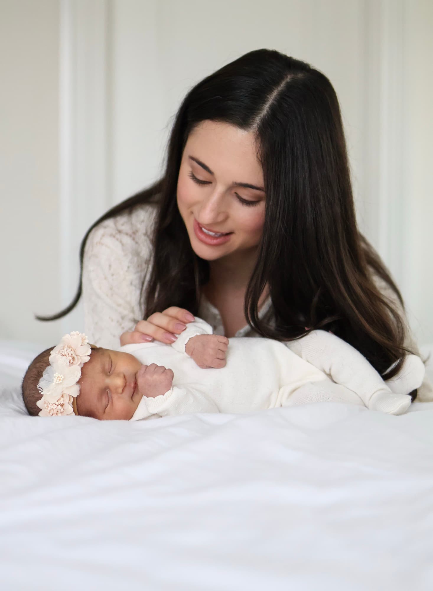 Mother gazing at newborn baby on bed — intimate newborn moment