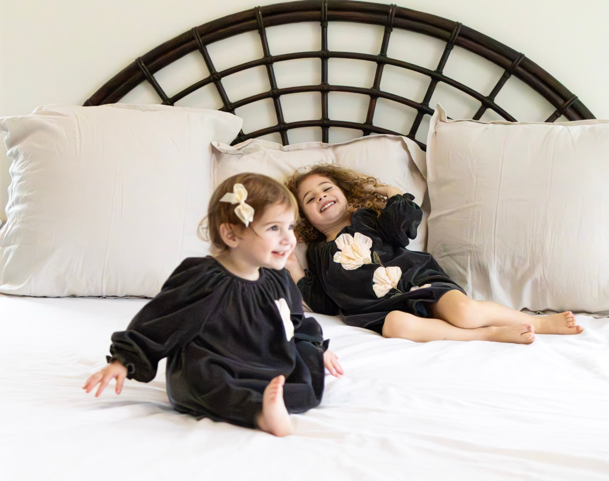 Two sisters laughing on bed — lifestyle sibling photography