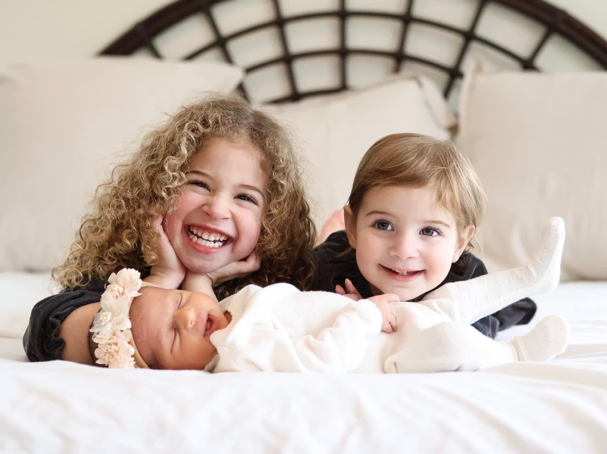 Big sisters smiling with newborn baby — sibling newborn photography