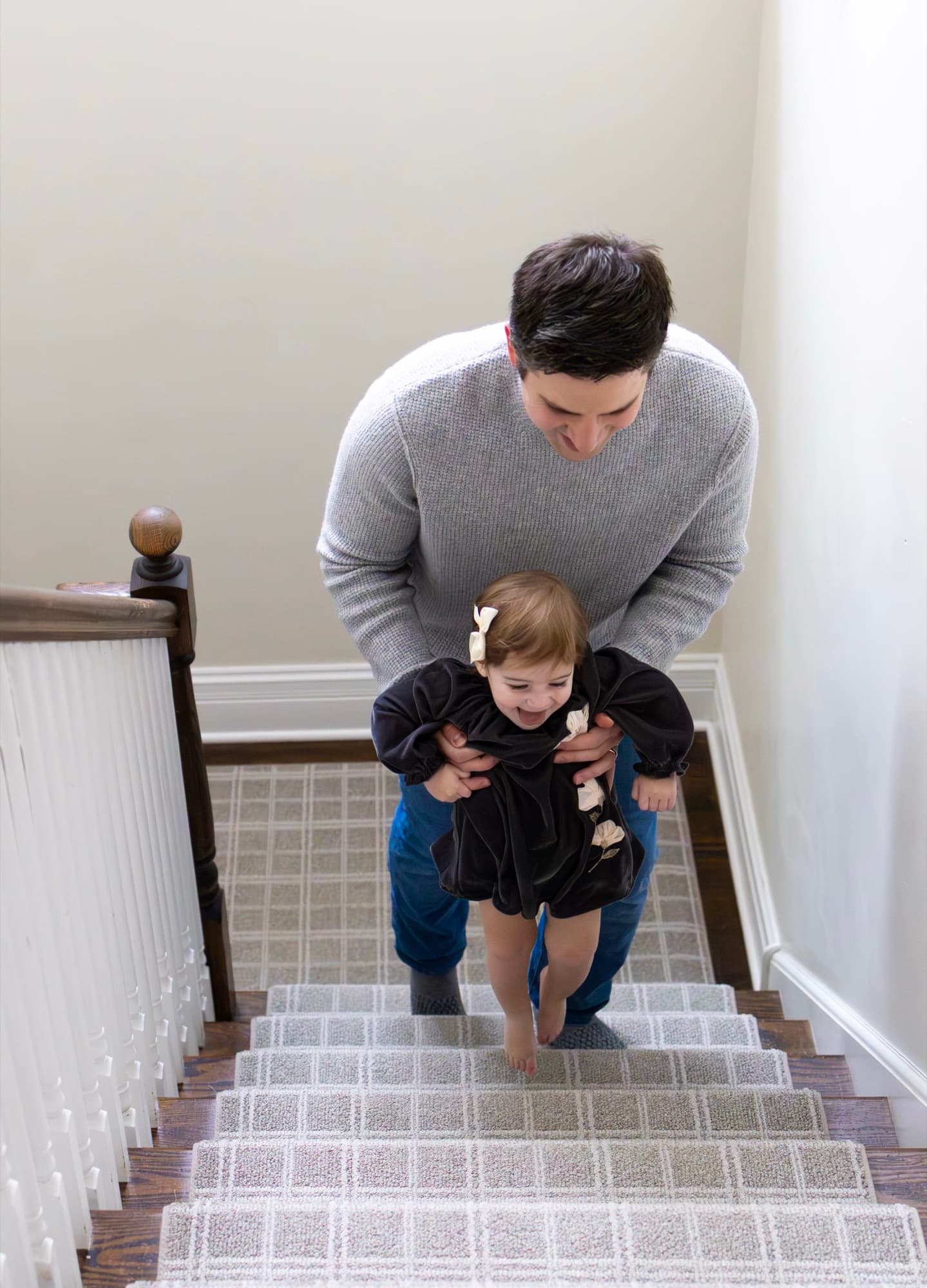 Father helping daughter walk down stairs — lifestyle family moment