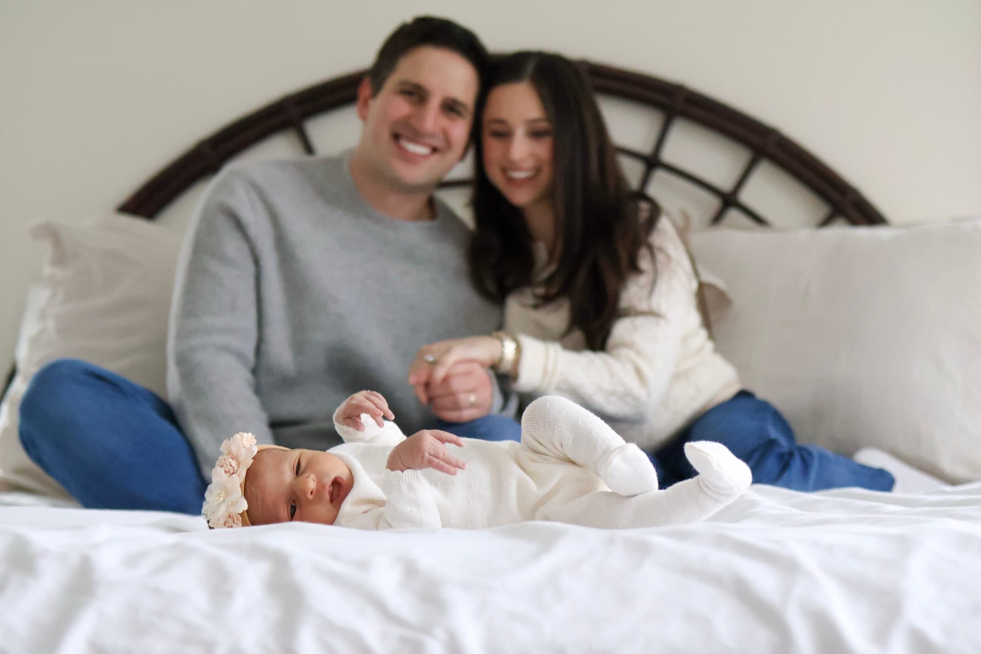 Parents watching newborn on bed — in-home newborn session