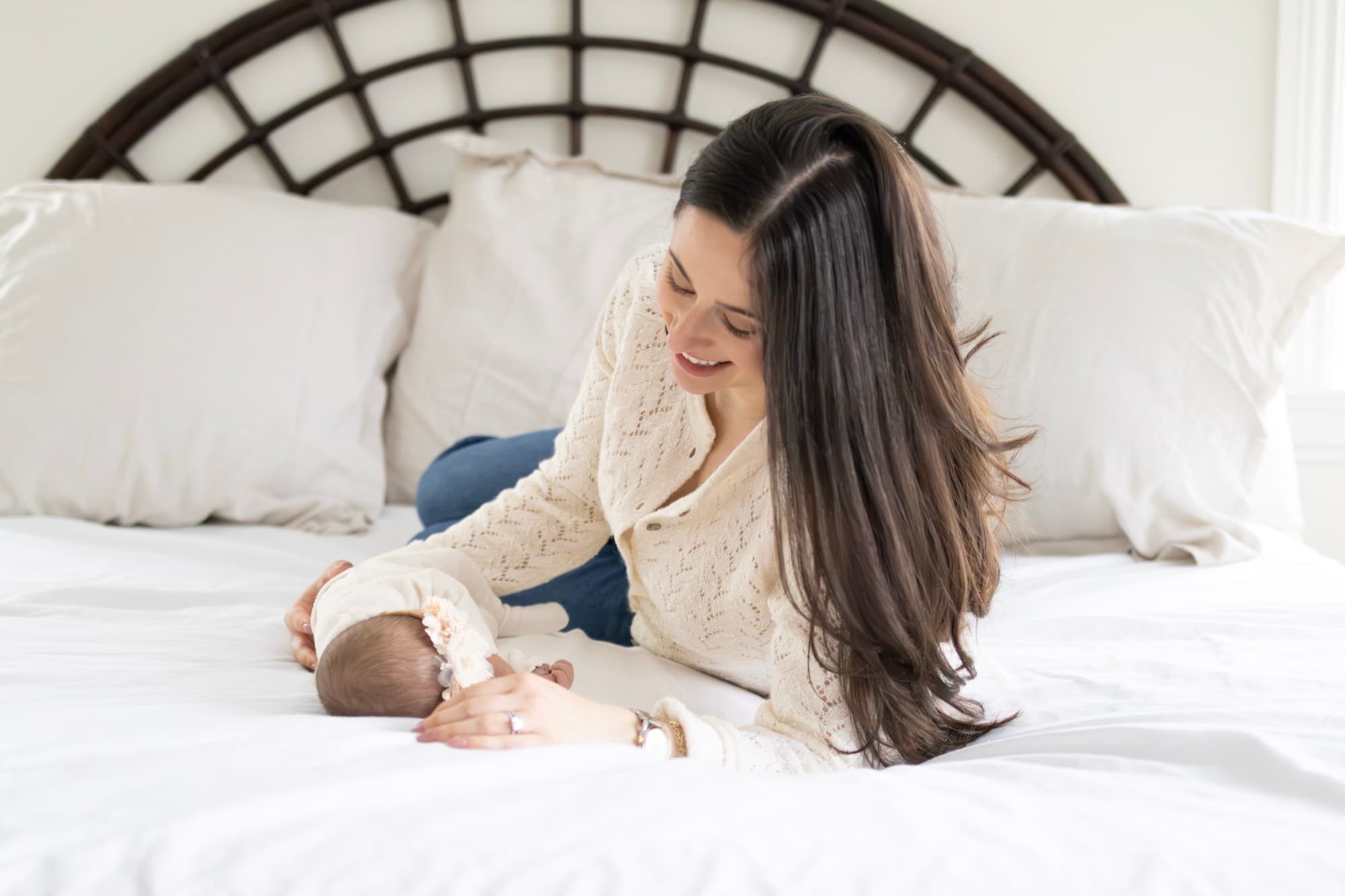 Mother lying with newborn on bed — intimate newborn photography
