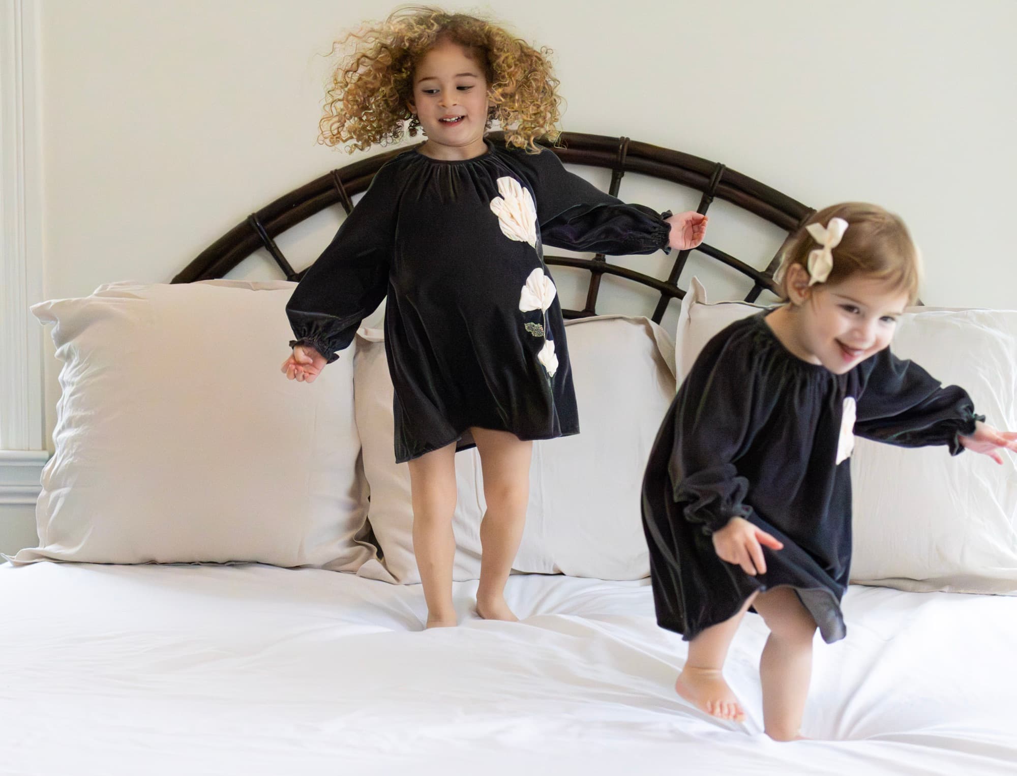 Sisters jumping on bed — playful childhood photography