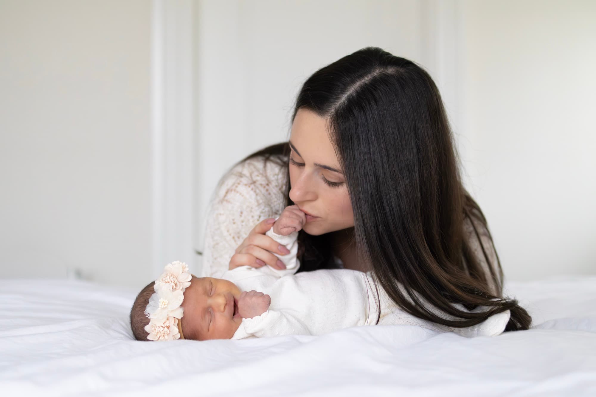 Mother kissing newborn baby's hand — tender newborn photography