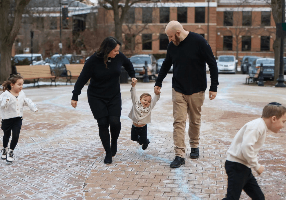 Skokie family photographer — parents swinging toddler on brick plaza during outdoor family session