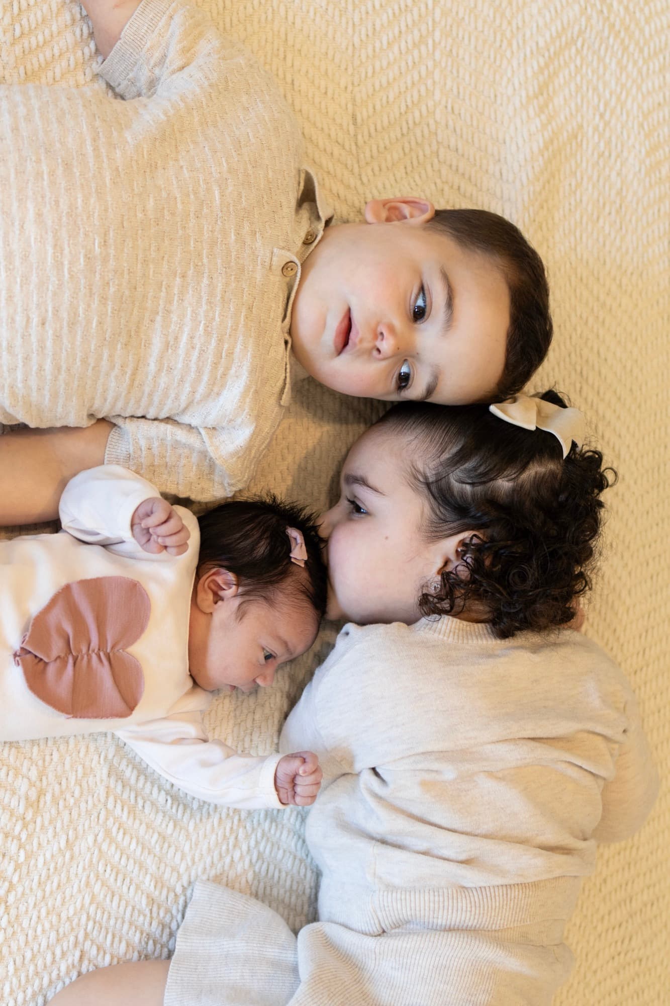 Three children lying together on blanket — sibling newborn photography