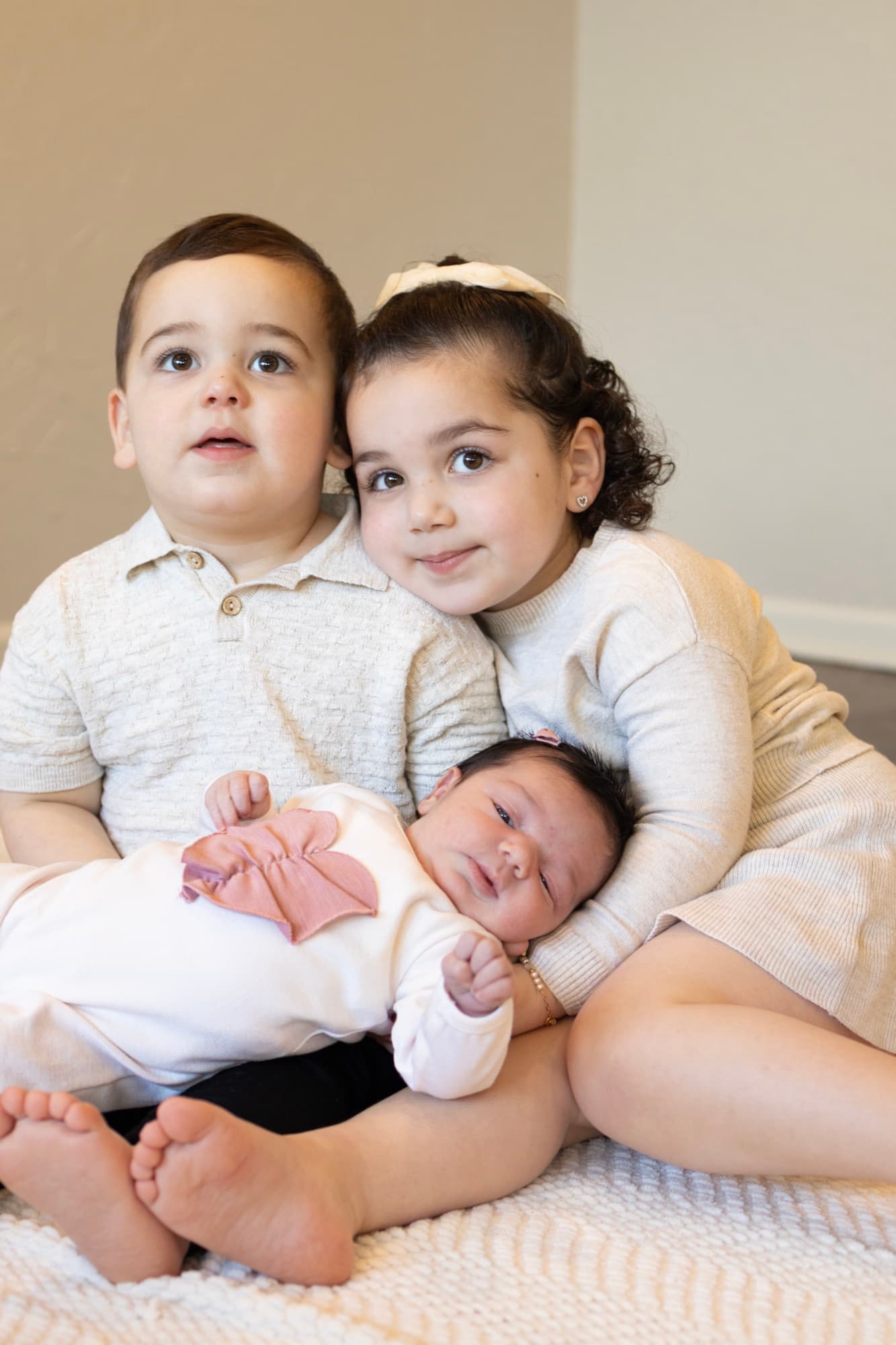 Siblings holding newborn baby — big brother and sister portrait