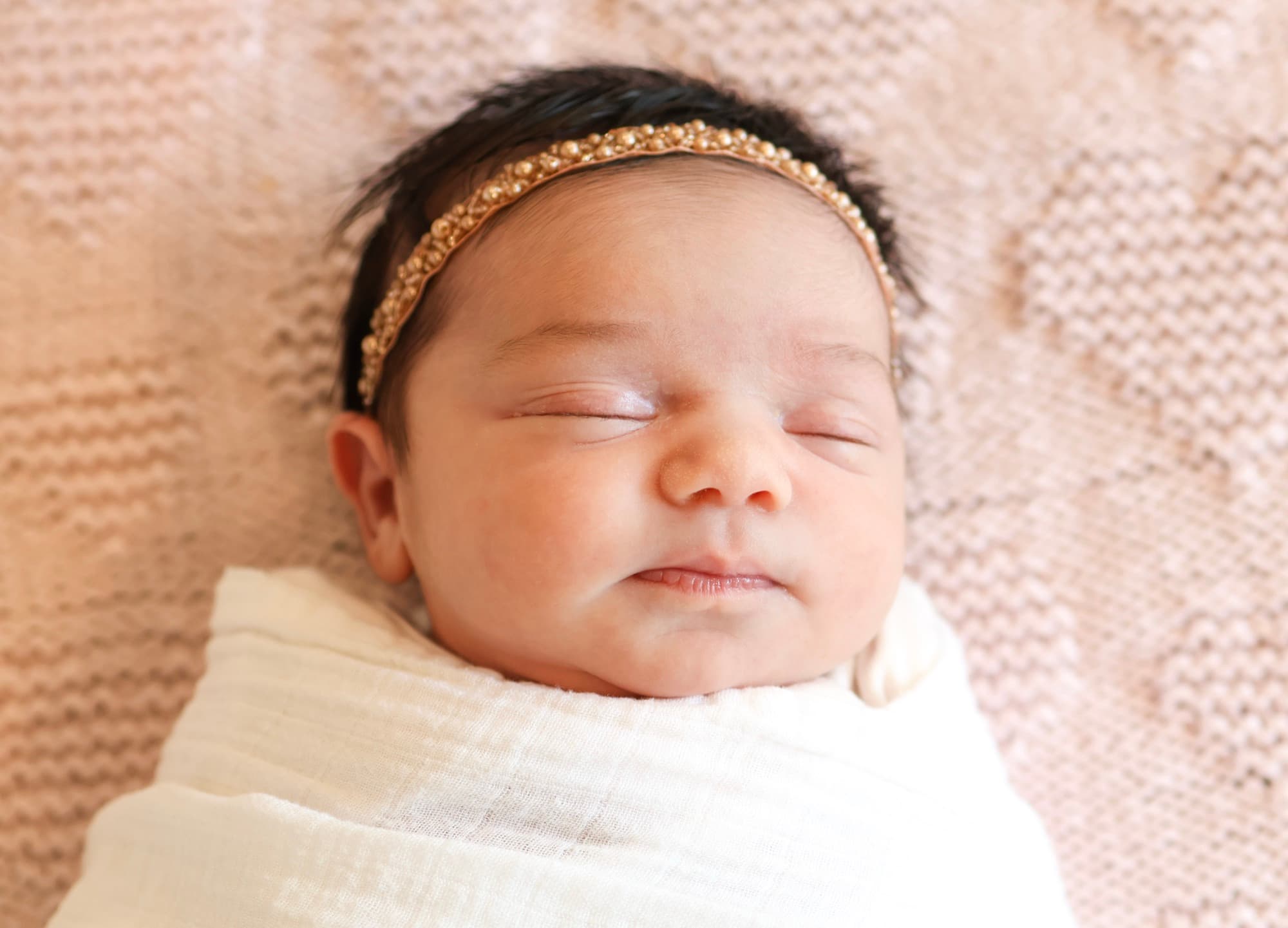 Newborn baby sleeping swaddled with gold headband — baby portrait
