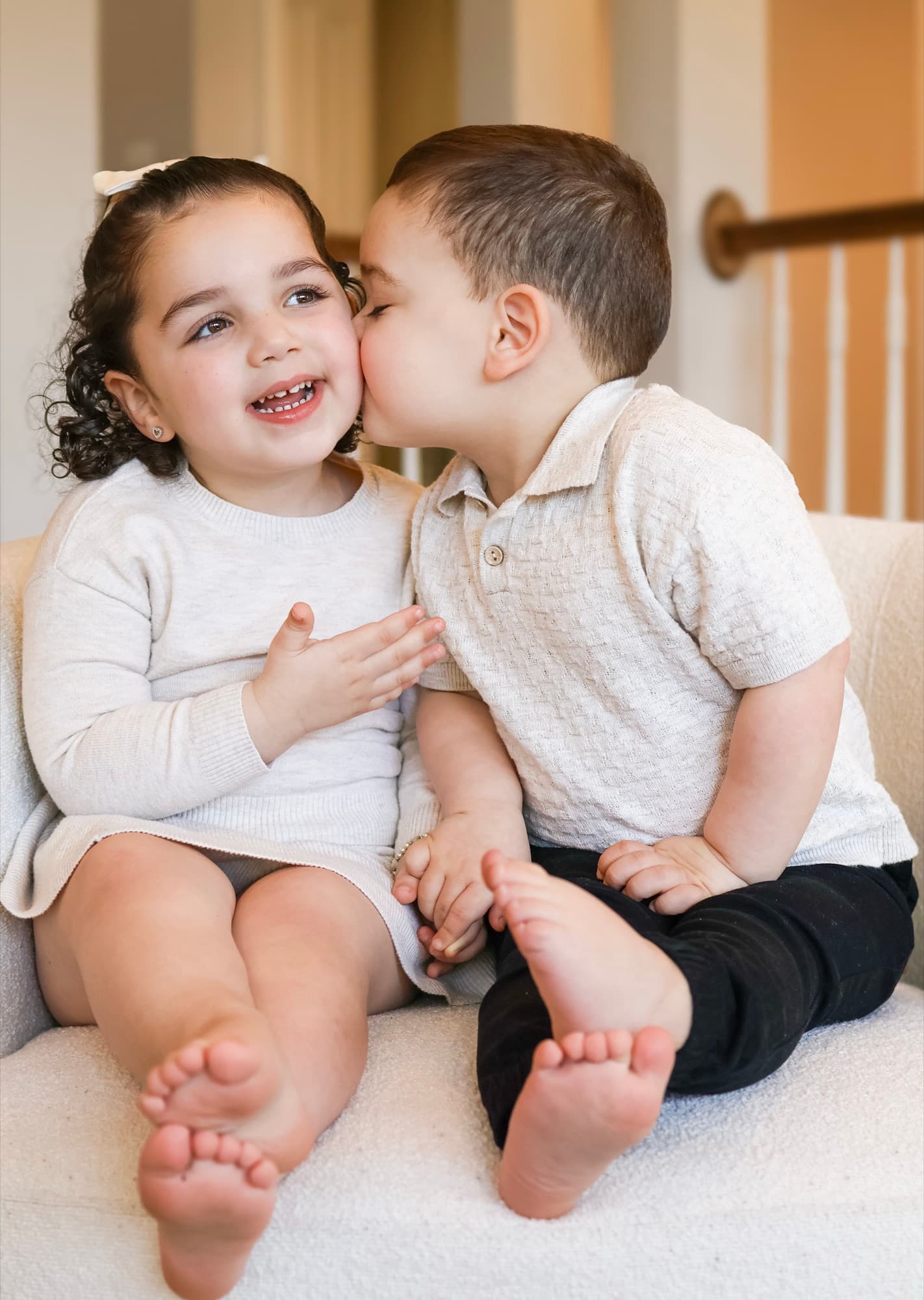 Brother kissing sister on cheek — playful sibling photography