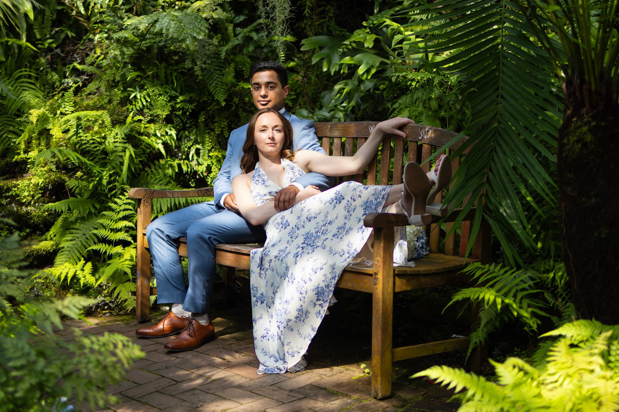 Engaged couple posing on a bench surrounded by tropical plants at Garfield Park Conservatory in Chicago