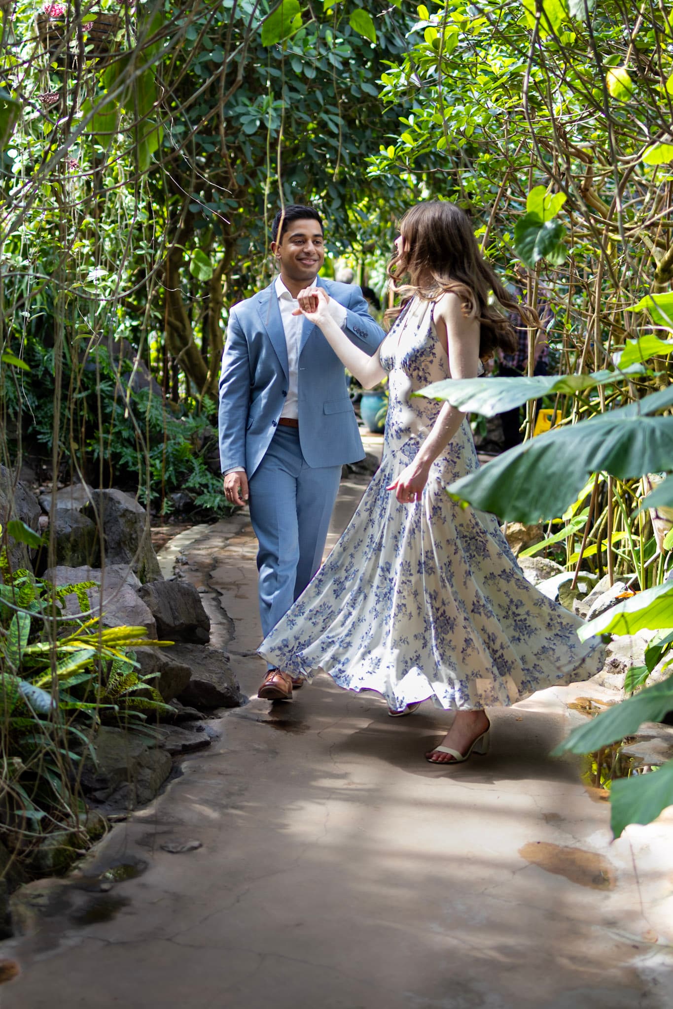 Couple walking through lush greenery during a Garfield Park Conservatory engagement photo session