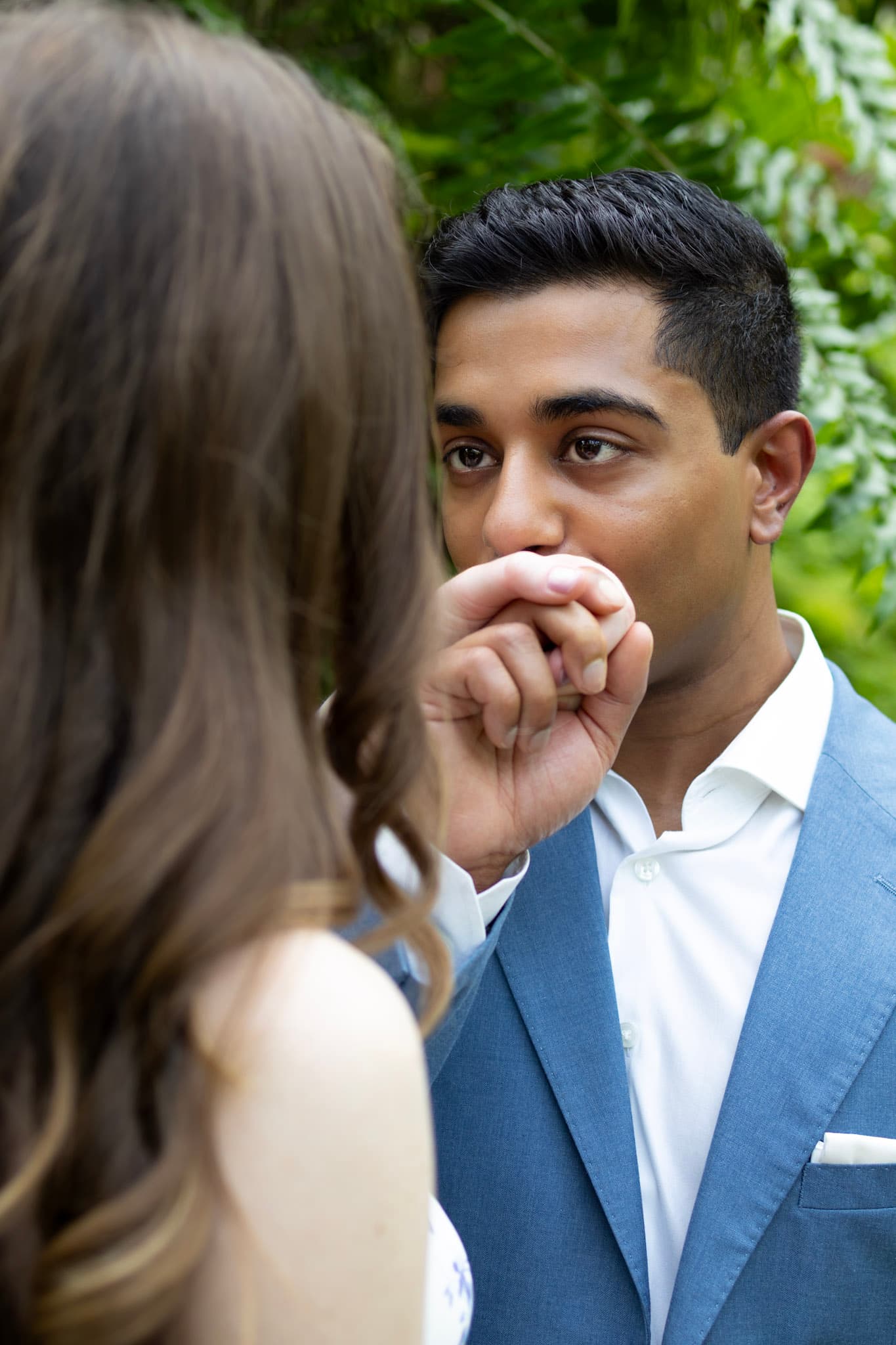 Candid close-up of groom kissing his fiancee's hand during an engagement session in Chicago