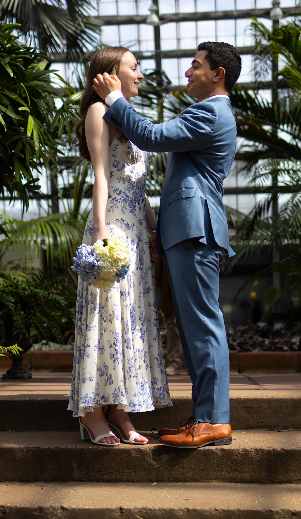 Engaged couple standing together with bouquet on conservatory steps in Chicago
