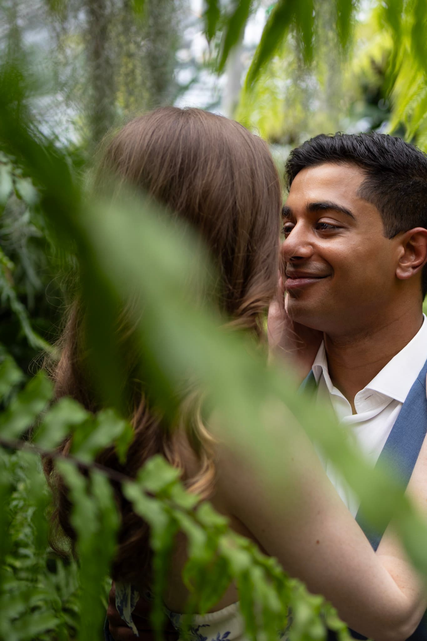Intimate engagement portrait through leafy foreground at Garfield Park Conservatory