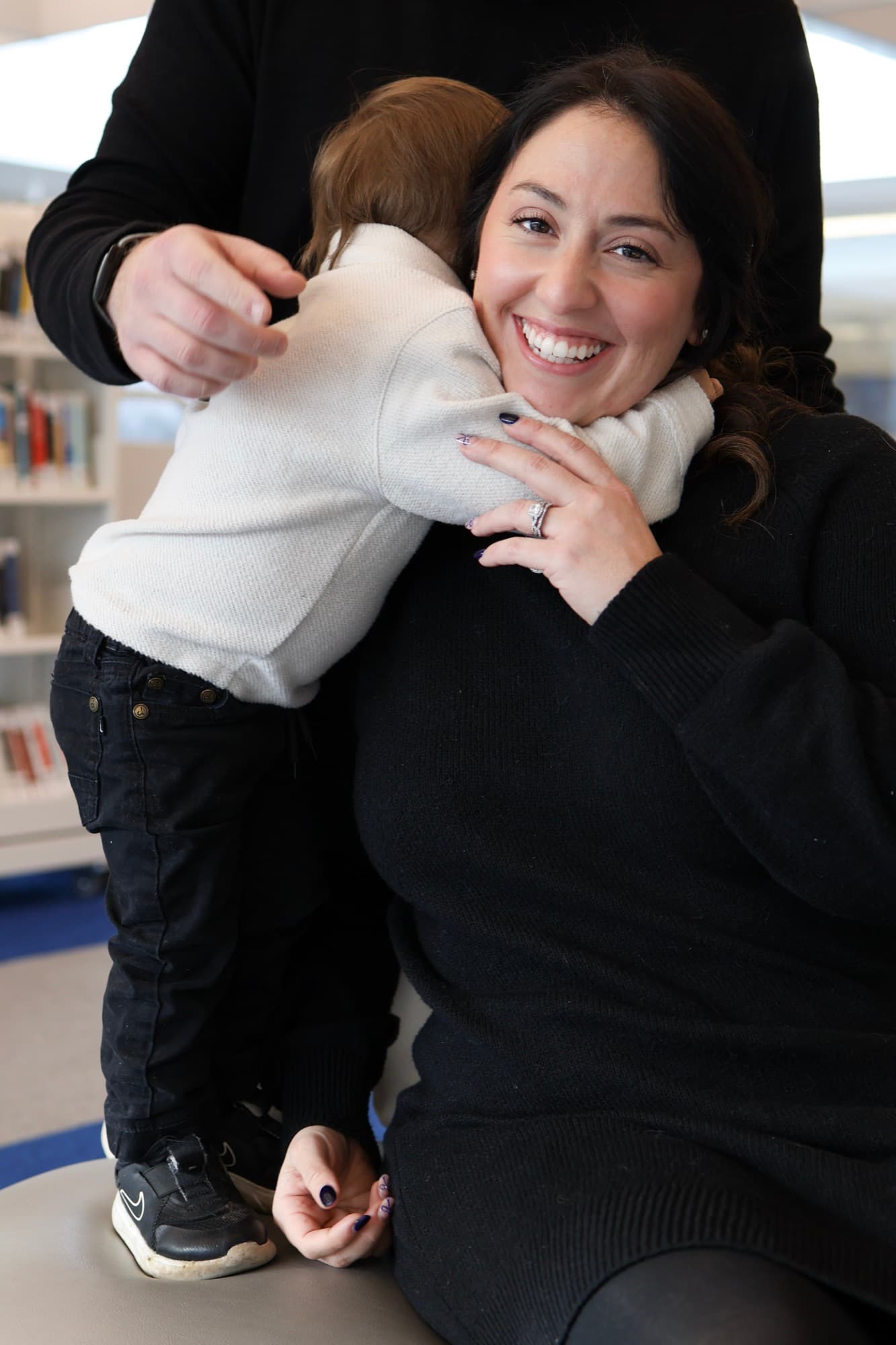 Toddler hugging mom in library — tender family moment