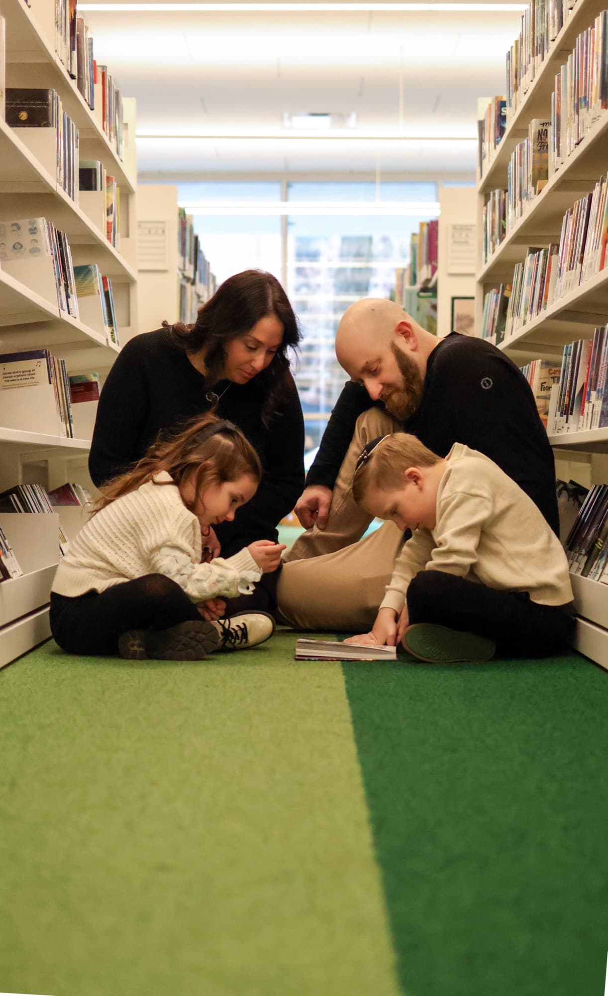 Family reading together in library aisle — Skokie Public Library family session