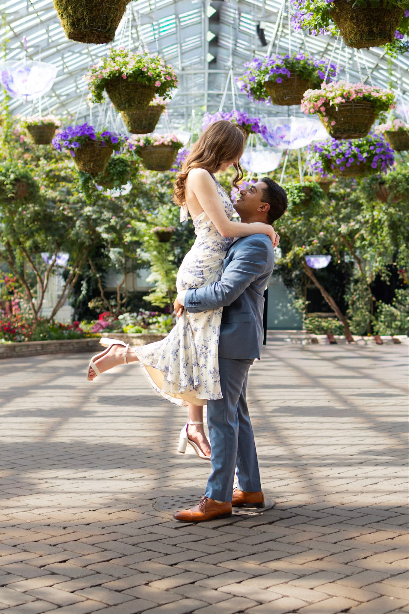 Engaged couple embracing beneath hanging flowers at Garfield Park Conservatory in Chicago