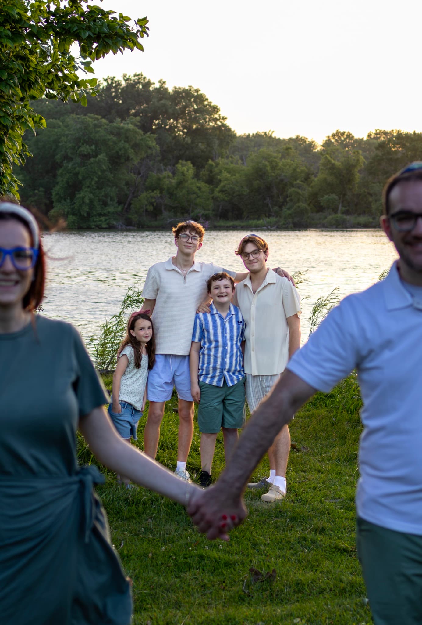 Four kids by the lake framed through their parents holding hands — creative family photography