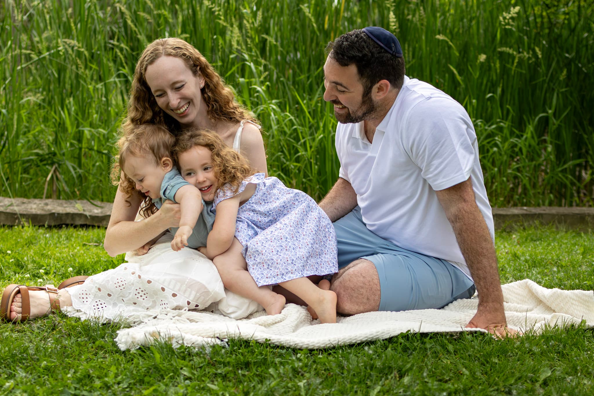 Family of four cuddling on white blanket in tall prairie grasses during Wilmette outdoor family photo session