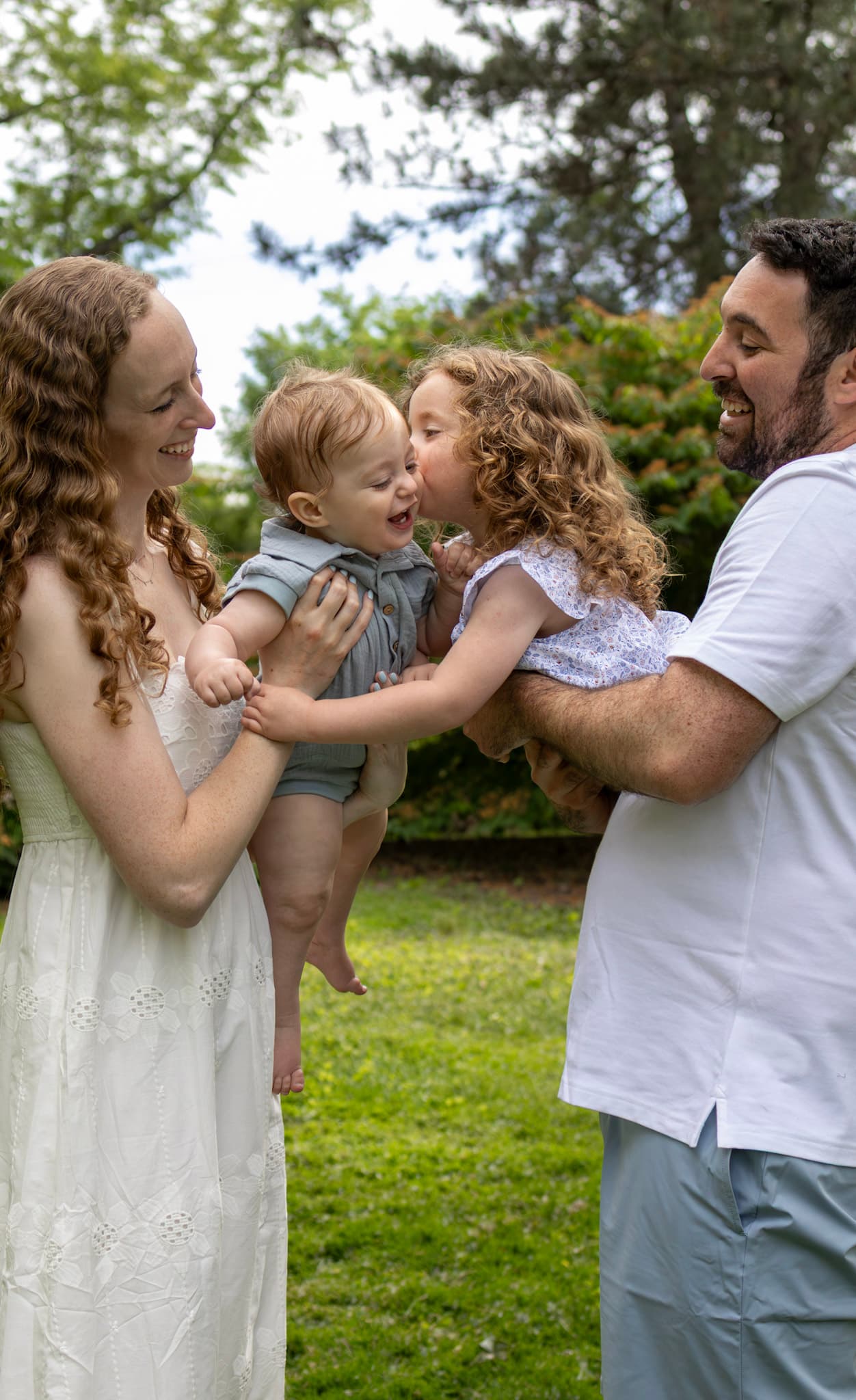 Mom kissing toddler son while big sister kisses too — candid Keay Nature Center family session in Wilmette