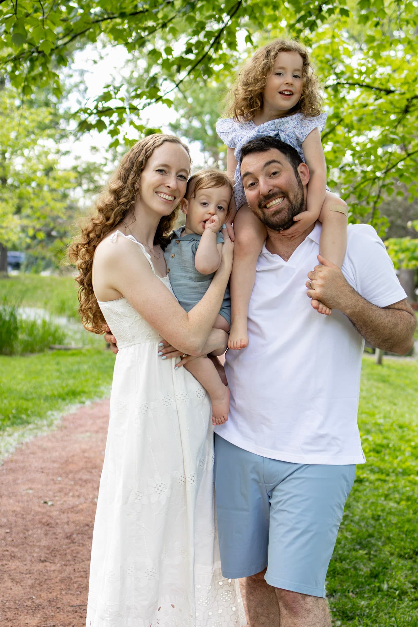 Family of four laughing with toddler daughter on dad's shoulders during a Wilmette outdoor family session