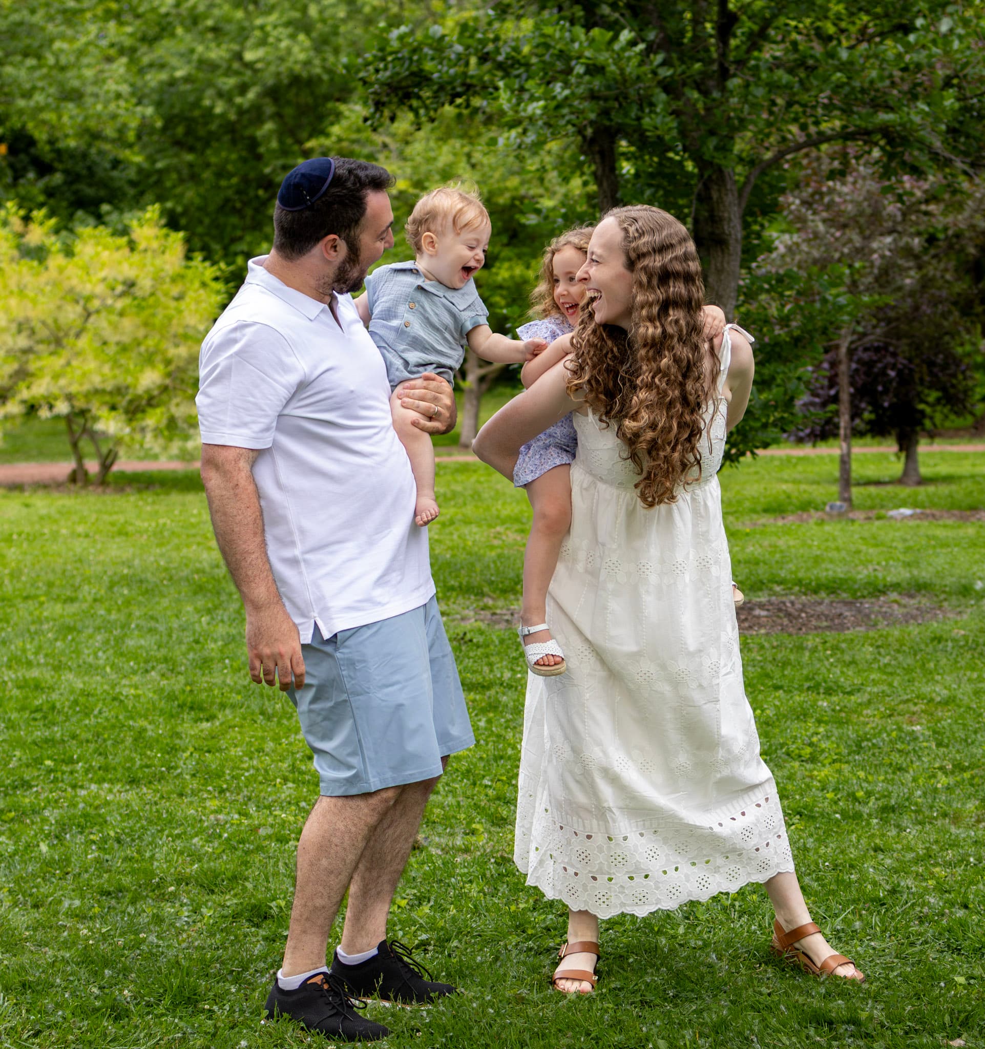 Family of four laughing together in a sunny clearing during a Wilmette family photography session