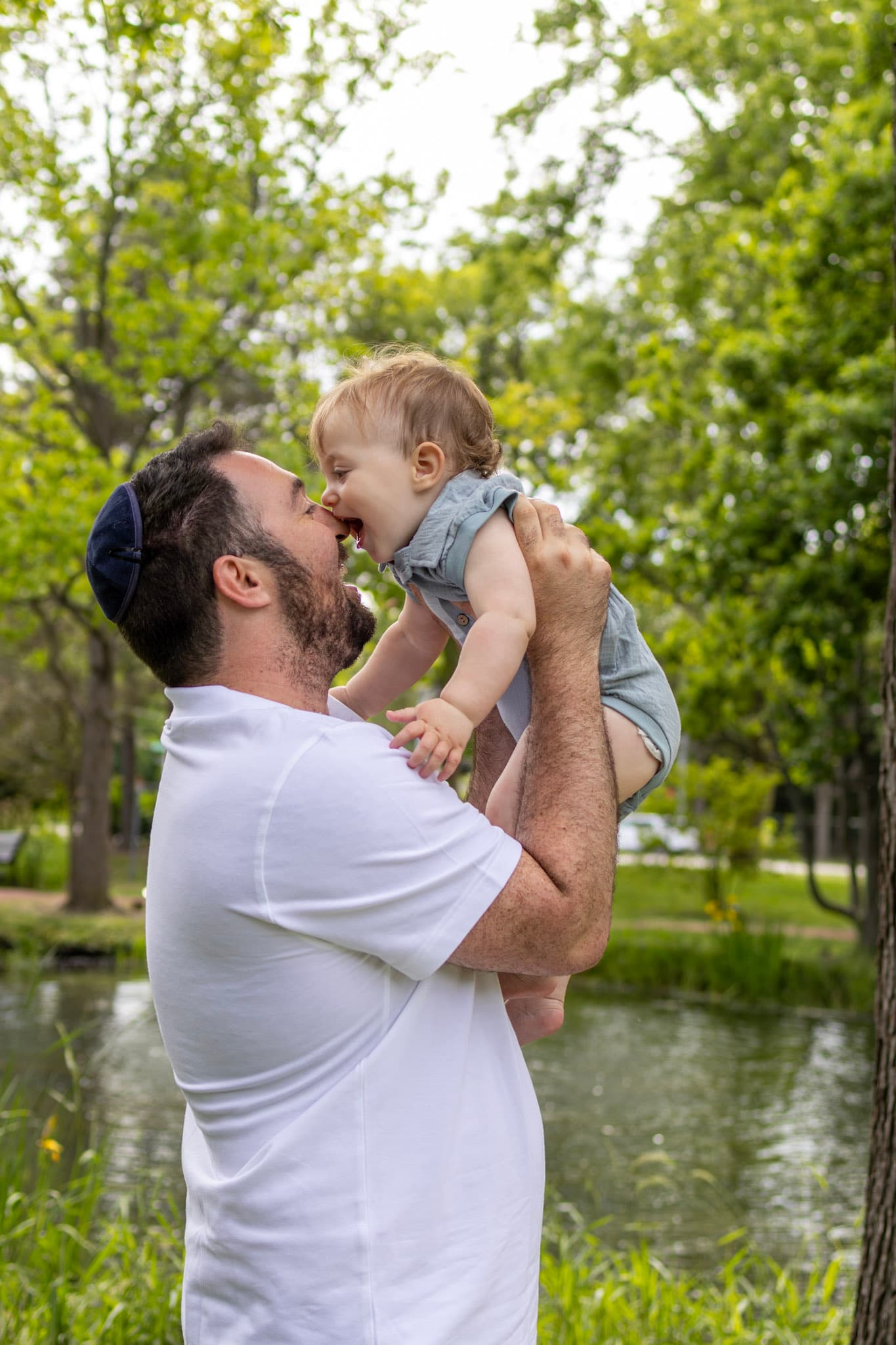 Dad lifting toddler son for a playful kiss by the pond at Keay Nature Center in Wilmette