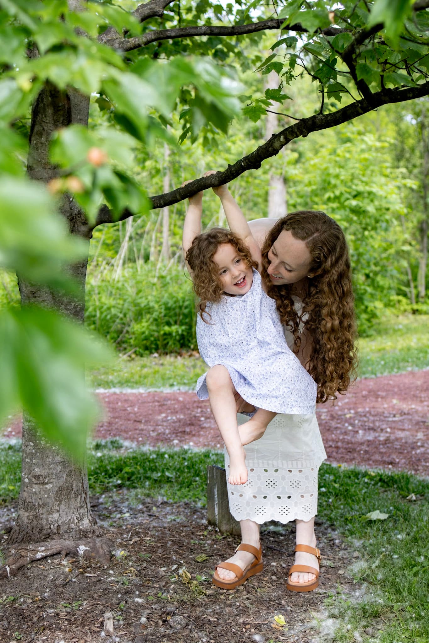 Mom and daughter swinging on a low tree branch in the woods at Keay Nature Center