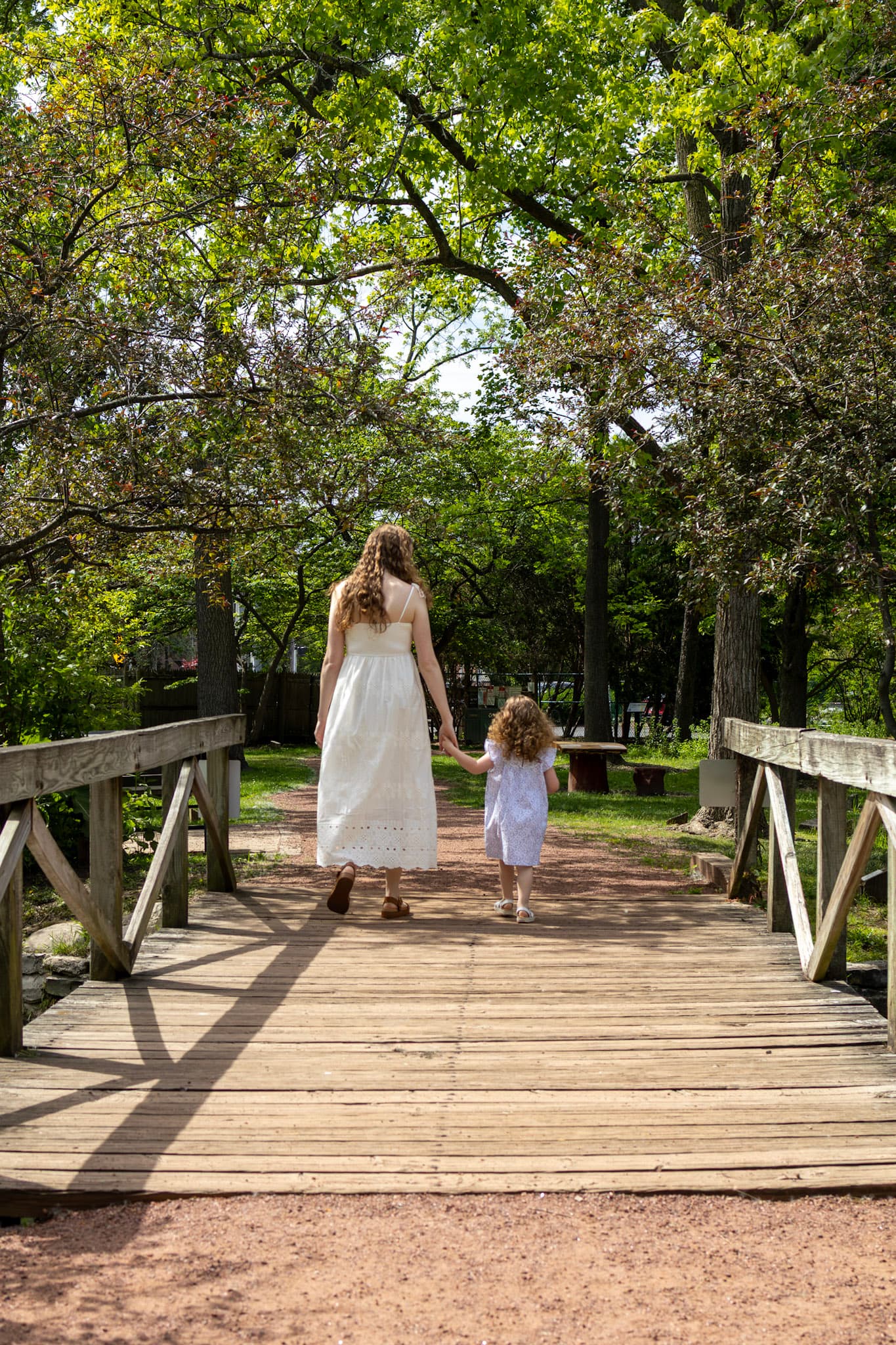 Mom and daughter walking hand in hand across a wooden bridge at Keay Nature Learning Center in Wilmette