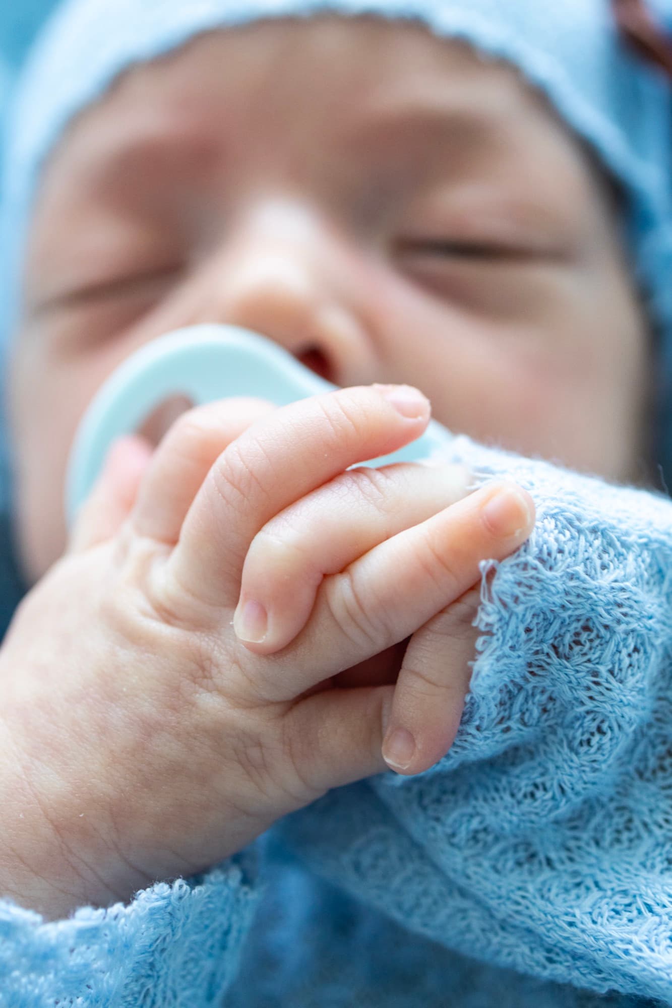 Newborn hand close-up with pacifier — baby detail photography