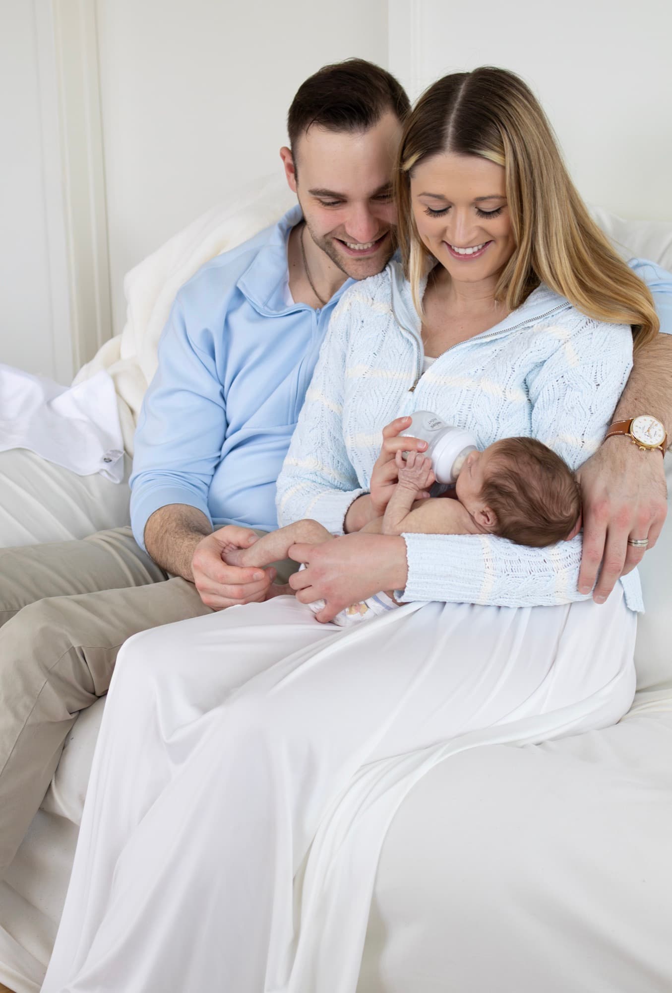 Parents feeding newborn baby on bed — candid lifestyle newborn photography