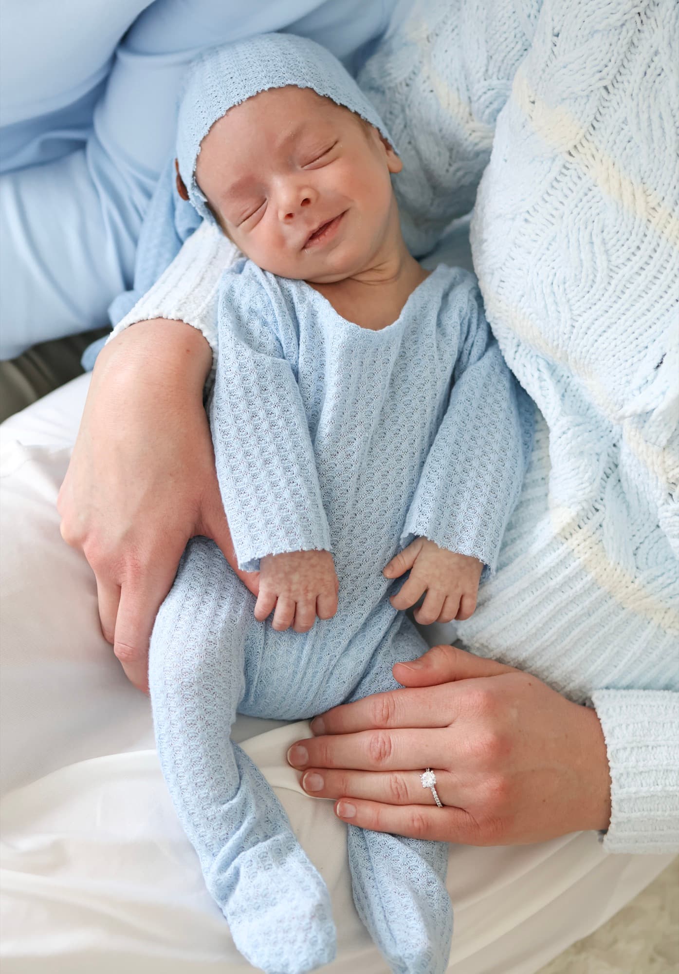 Newborn baby in blue outfit on mother's lap — lifestyle newborn