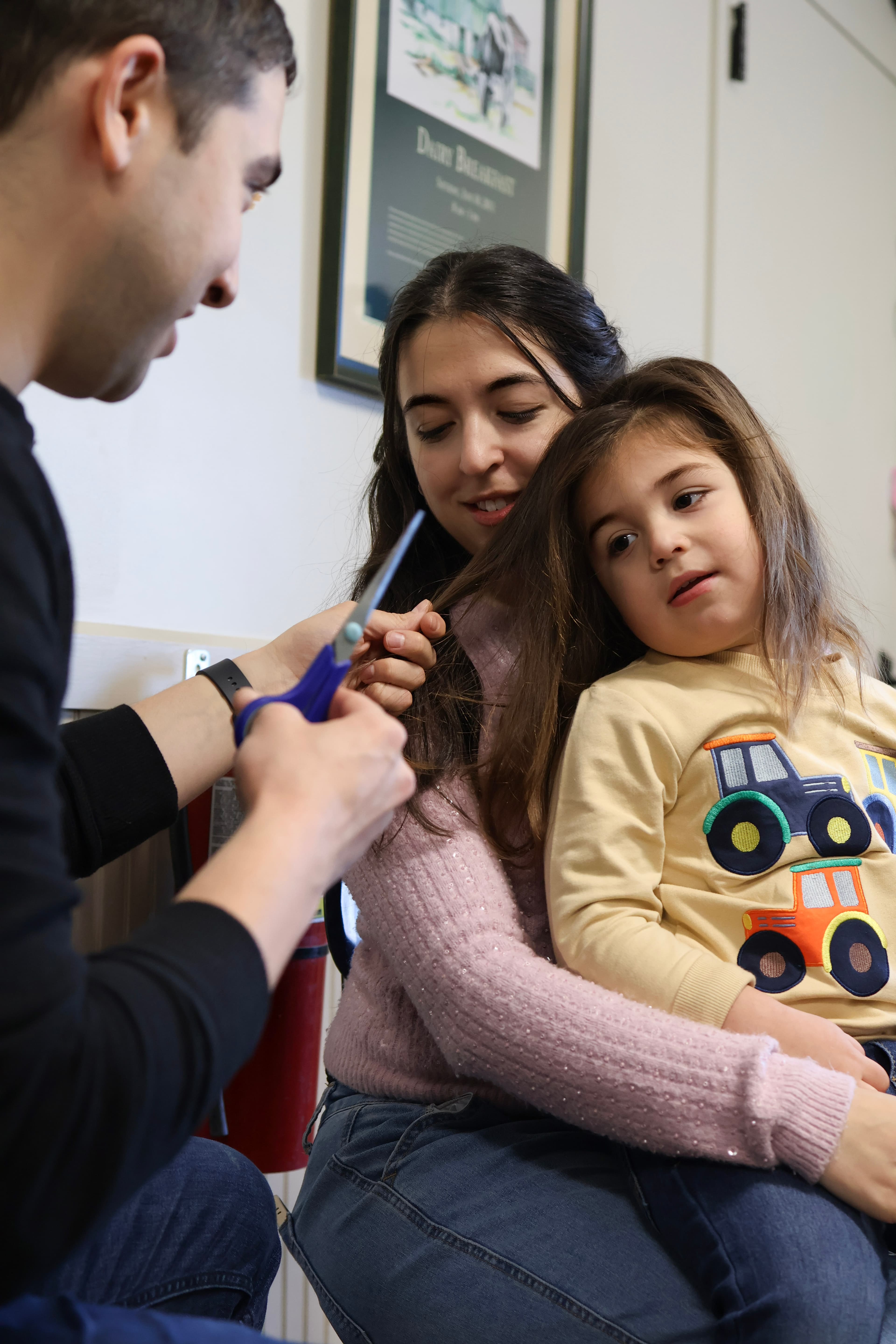 Close-up of father cutting daughter's hair during Upshirin — milestone detail