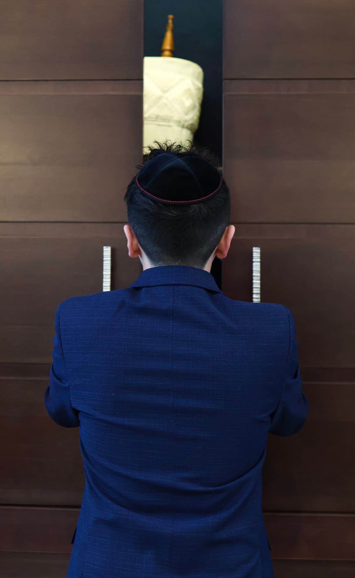 Bar Mitzvah boy opening the Torah ark — dramatic synagogue photography