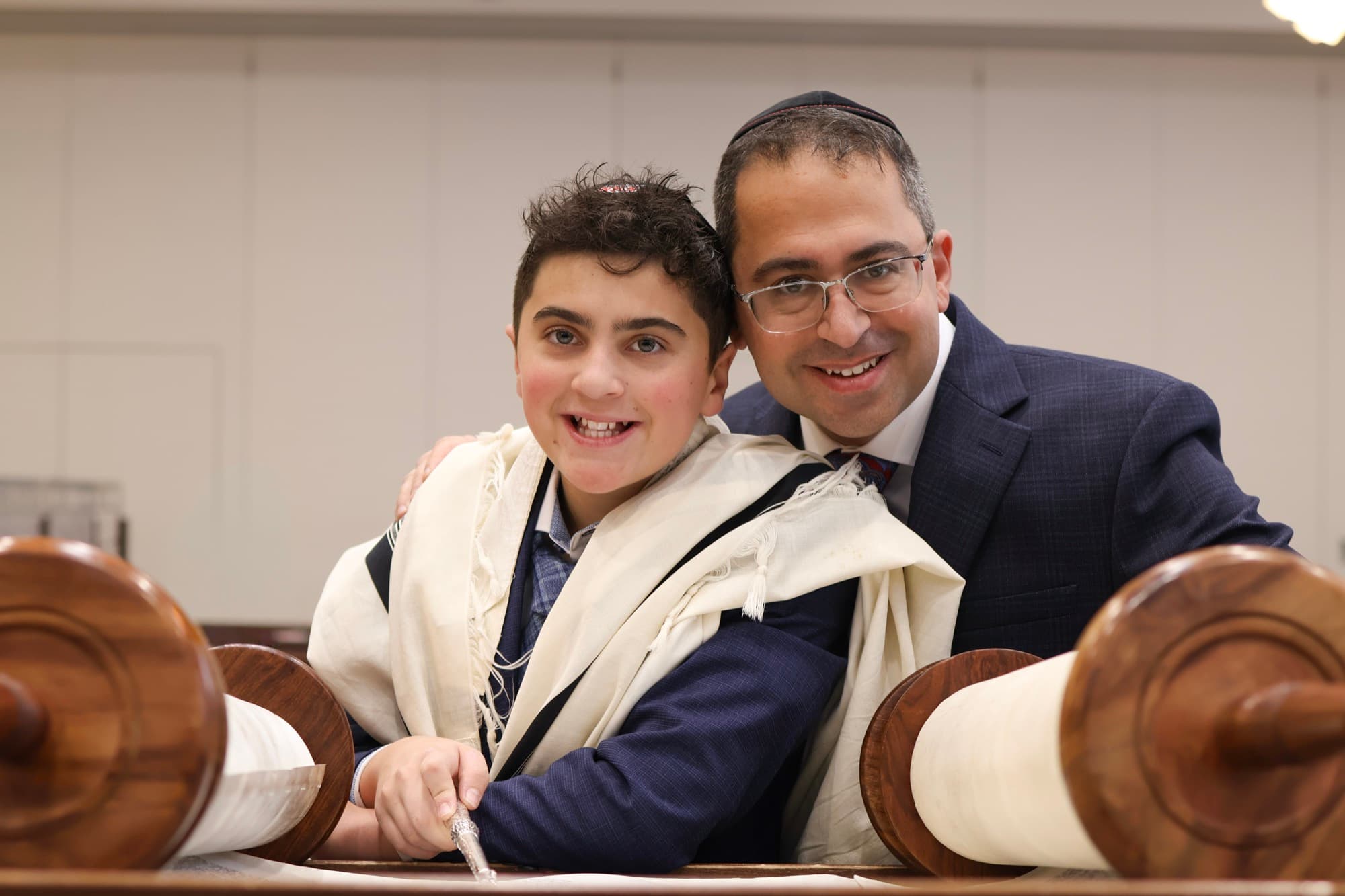 Father and son smiling with open Torah scroll — Bar Mitzvah ceremony