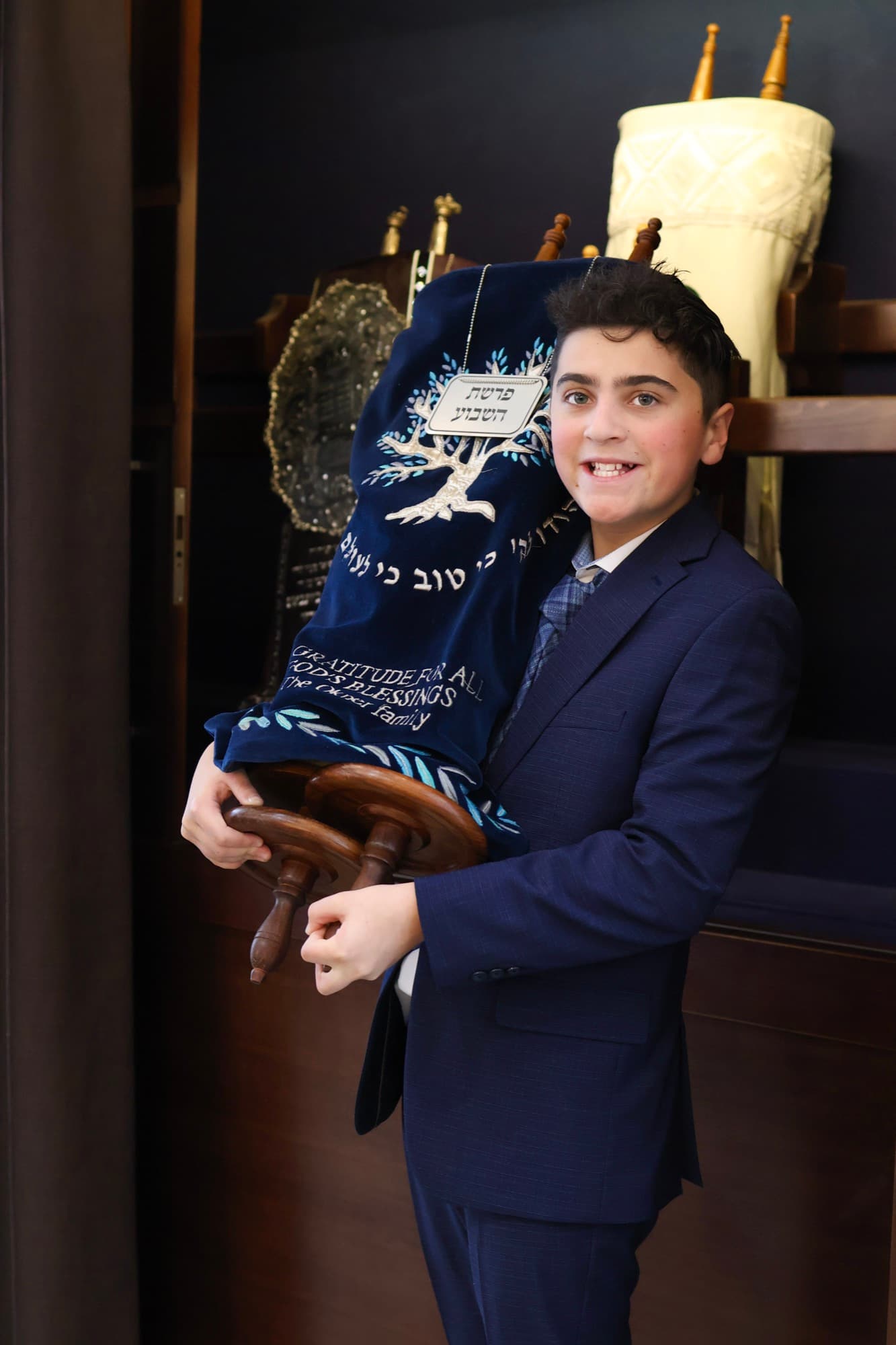 Bar Mitzvah boy proudly holding Torah scroll — milestone portrait