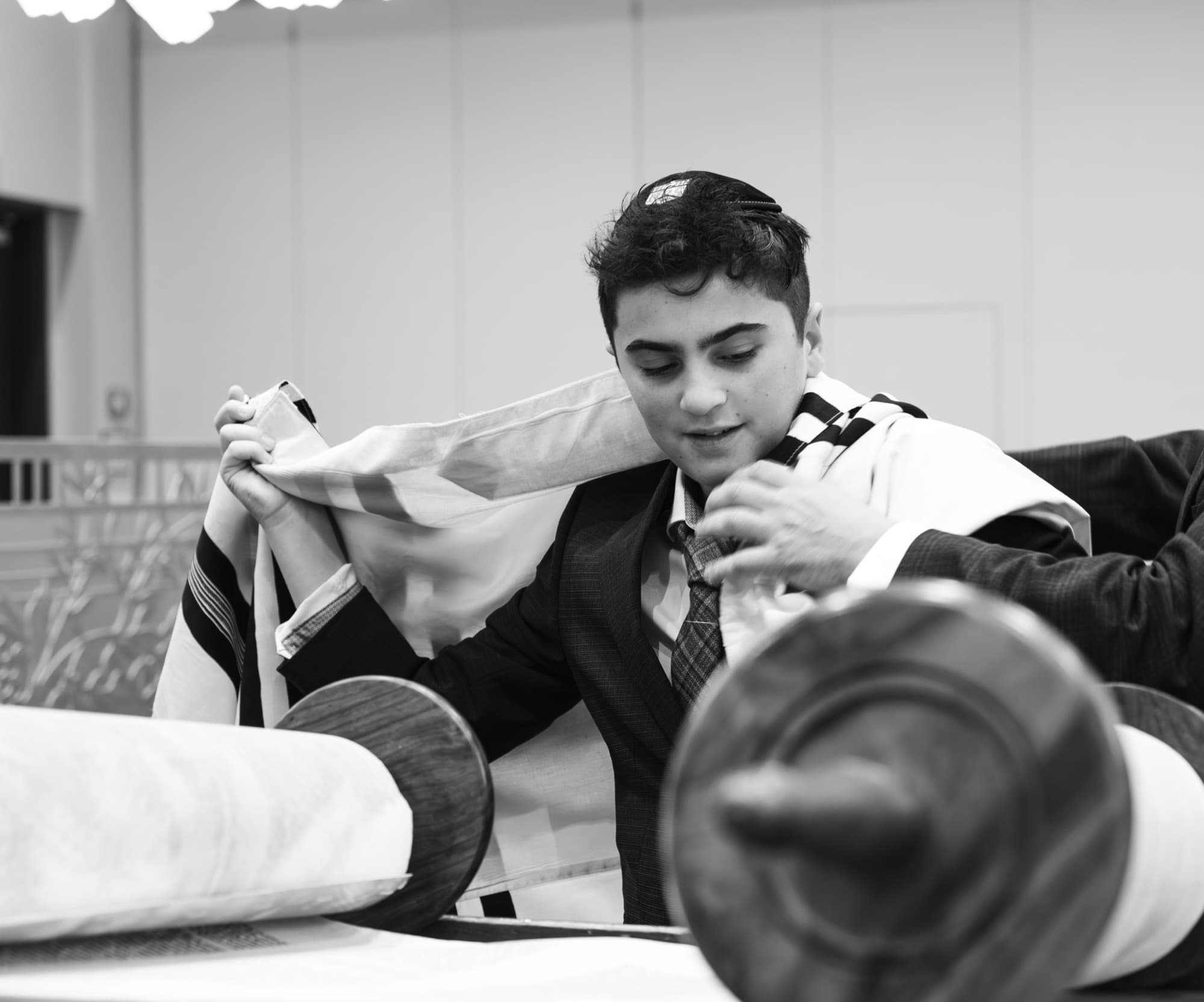 Bar Mitzvah photographer Skokie — boy putting on tallit prayer shawl during ceremony