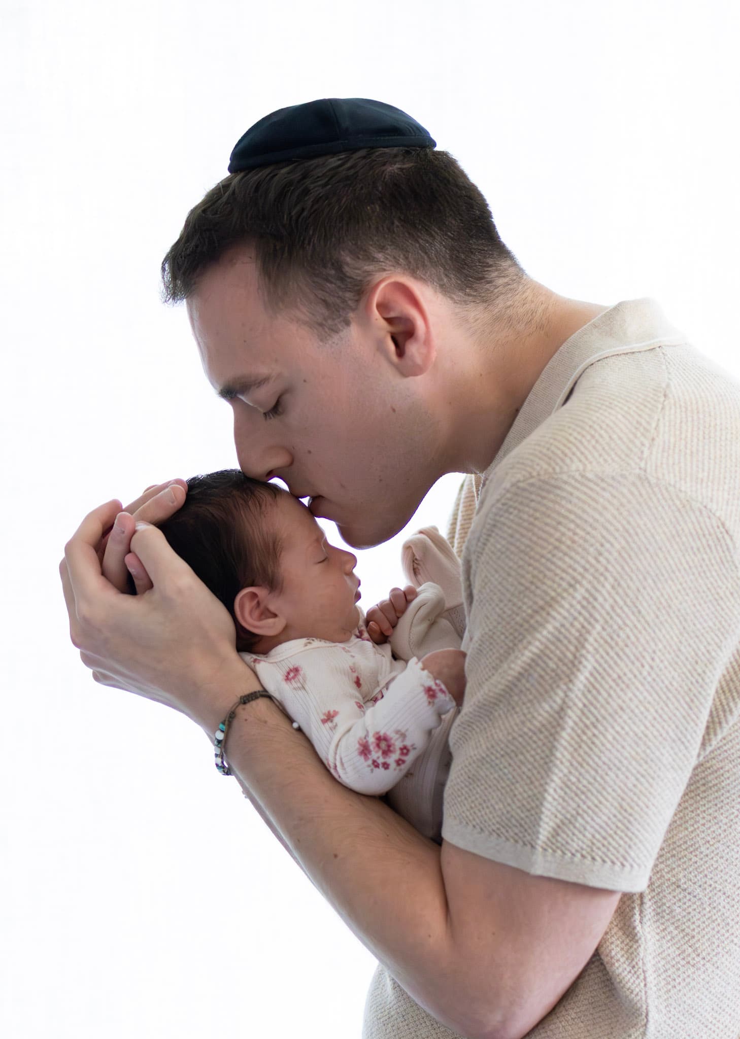 Dad kissing newborn baby girl's head during a Skokie studio newborn session with backlit window light