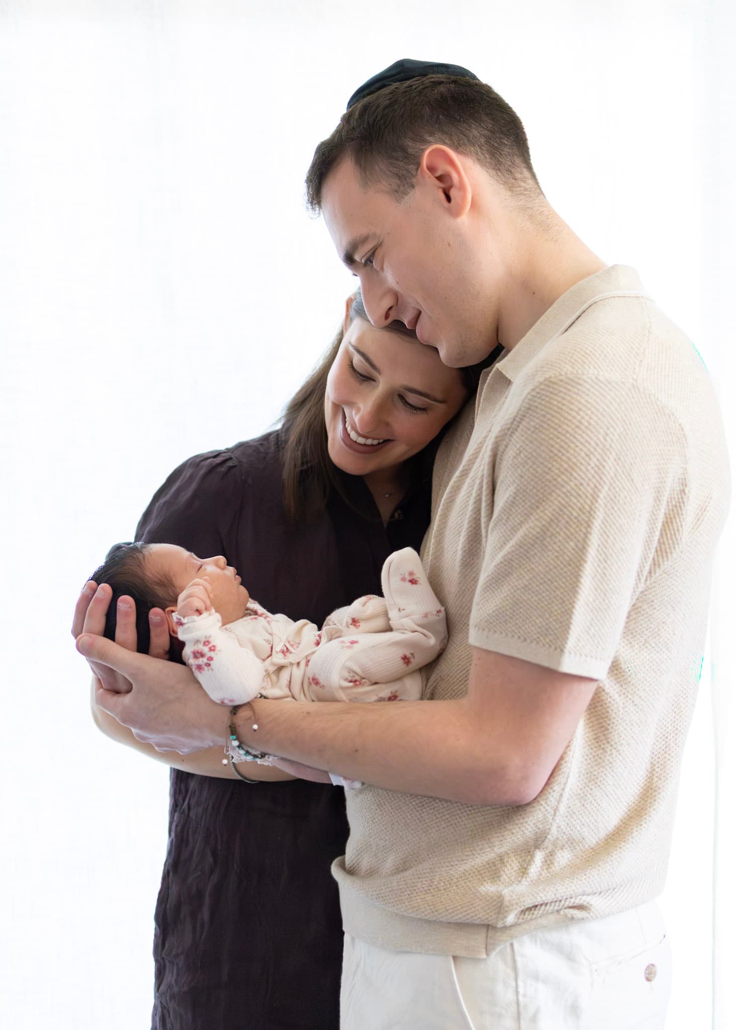 Mom kissing newborn baby girl's head during a soft natural light studio session in Skokie