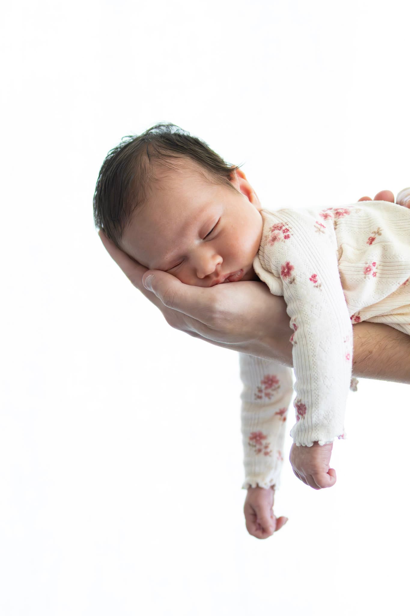 Newborn baby girl asleep in parent's hand during a studio session — gentle newborn portrait
