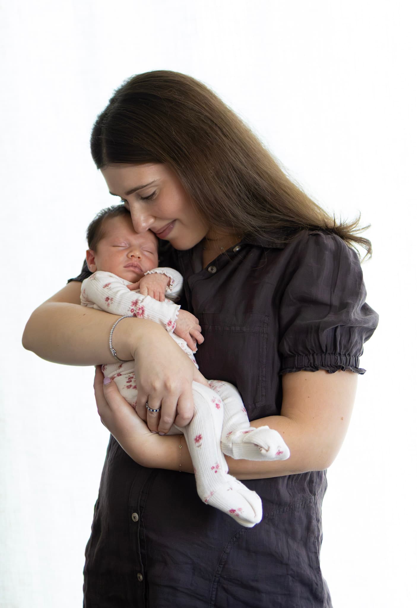 New mom holding her sleeping newborn baby girl during a Skokie studio newborn session