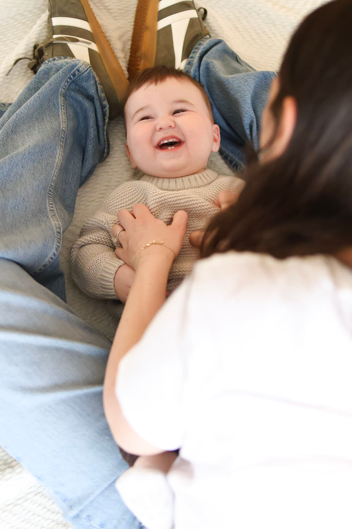 Laughing baby while being tickled by a parent during a lifestyle family photography session at home