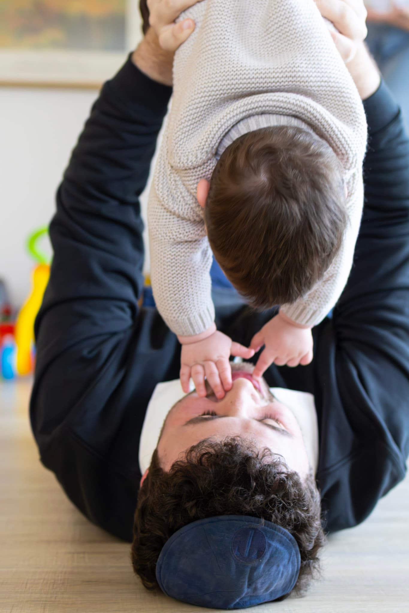 Father playing with 9 month old baby on the floor during a candid lifestyle family photo session