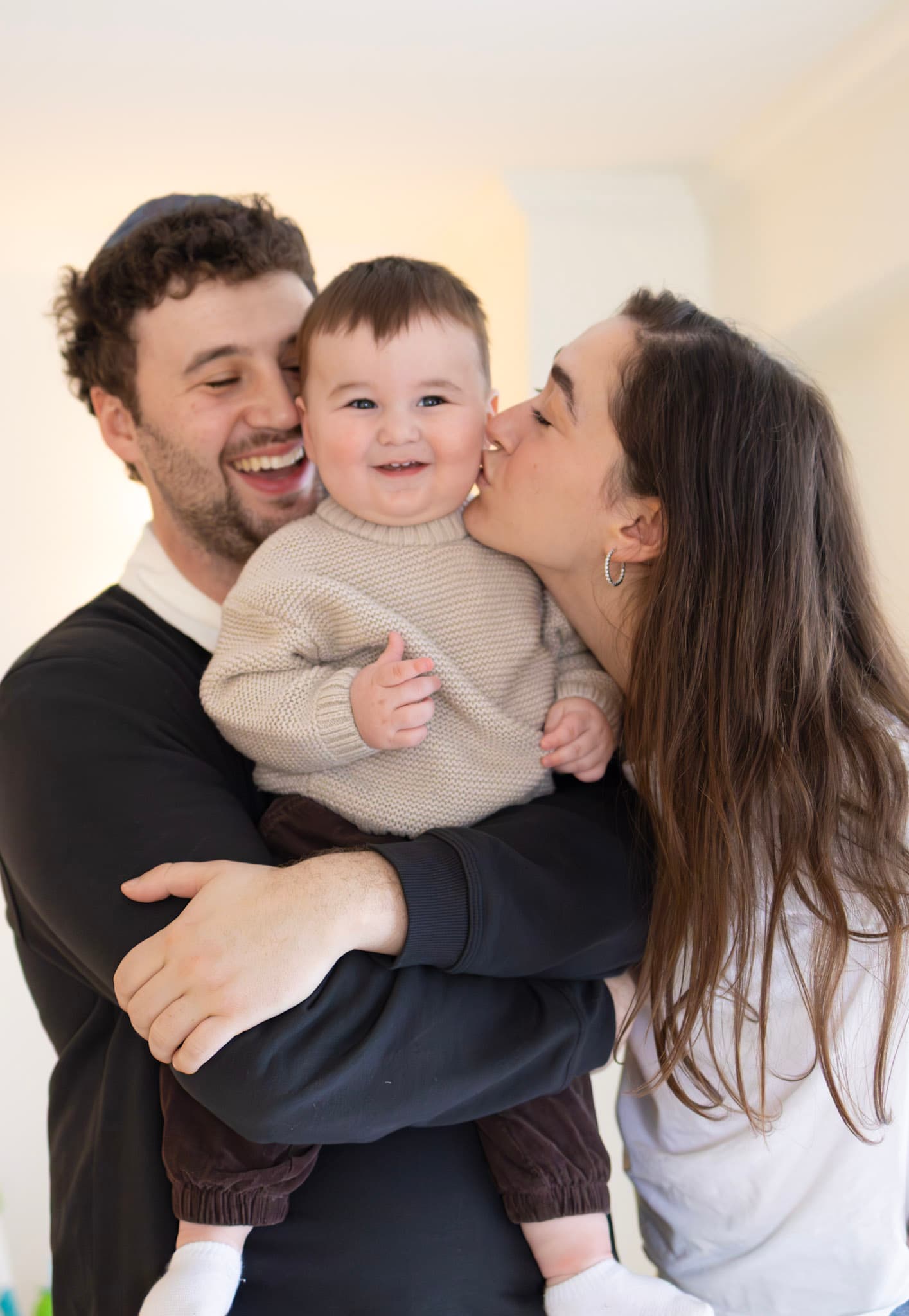 Parents kissing their 9 month old baby during an in-home family photography session in West Rogers Park